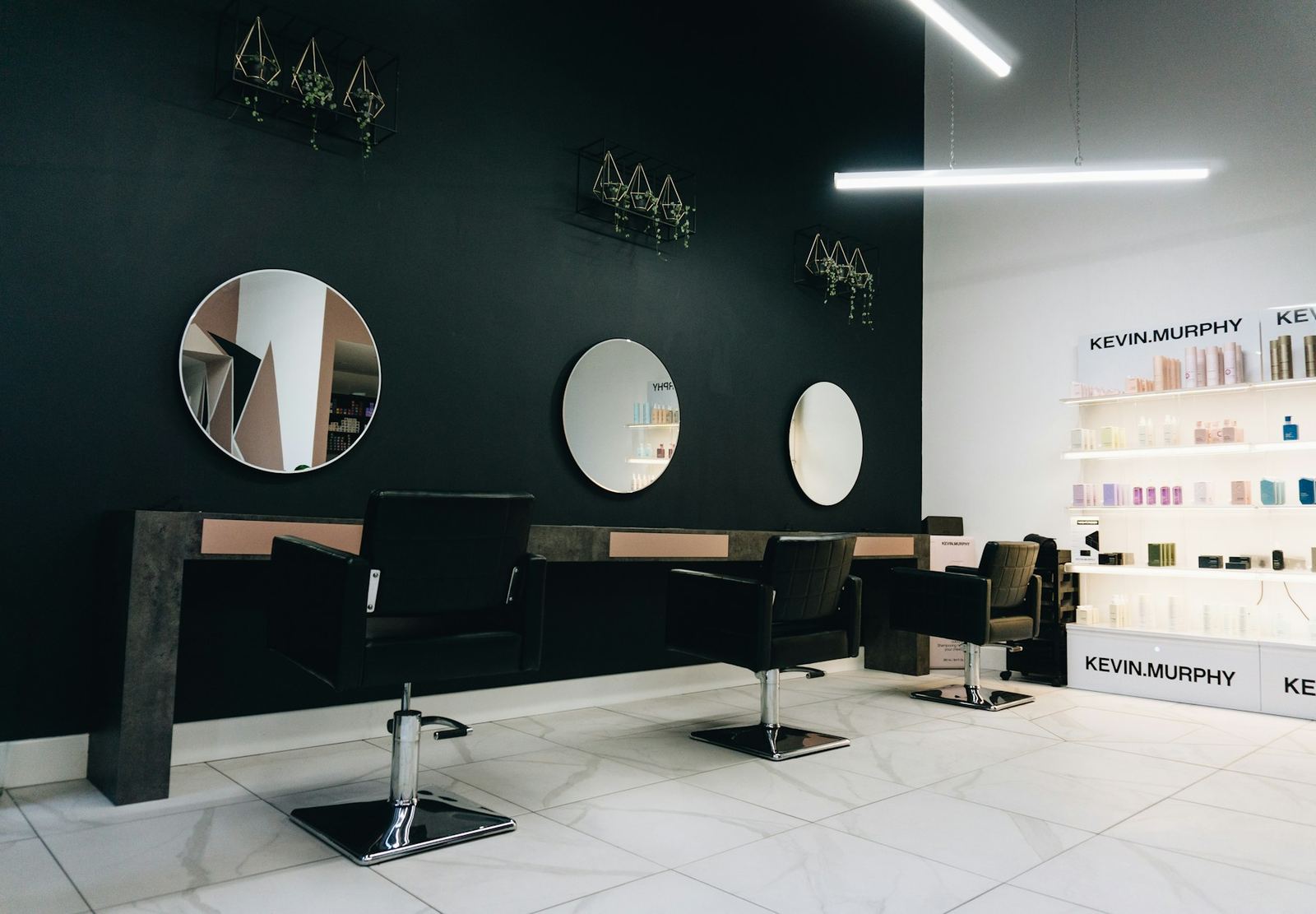 The styling floor at LUMEN, with round mirrors on a dark wall